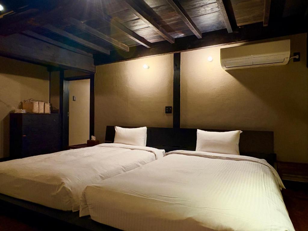 two beds sitting next to each other in a bedroom at ふくさぶろ in Ushikubi