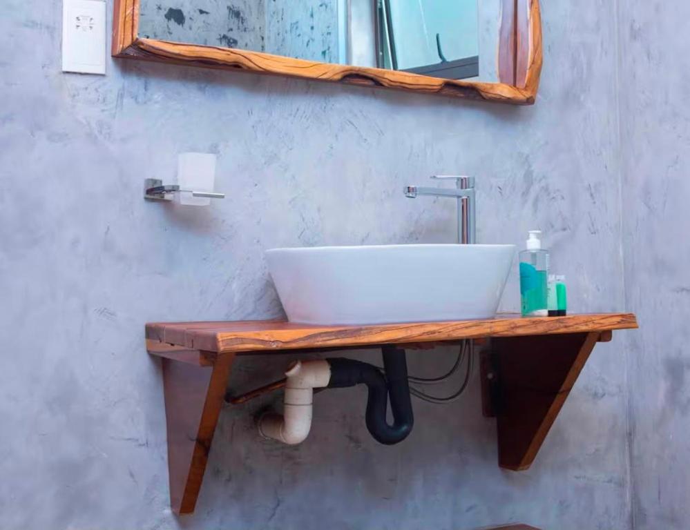 ein Waschbecken auf einer Holztheke mit einem Spiegel in der Unterkunft Narvira in Kona