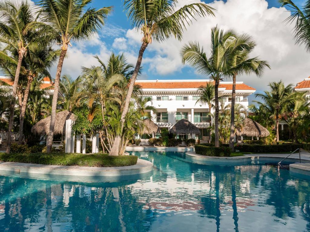 a pool in front of a resort with palm trees at Zel Punta Cana - All Suites - All Inclusive in Punta Cana