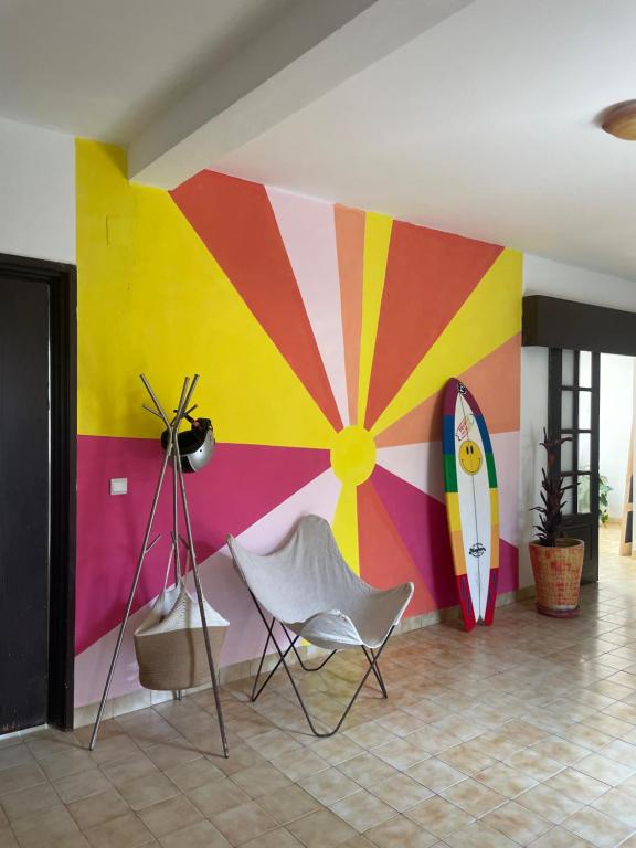 a room with a colorful wall with a surfboard and a chair at Malika Surf House in Dakar