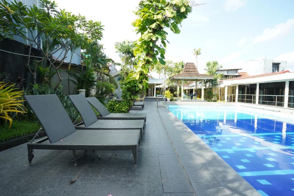 a row of chaise lounge chairs next to a swimming pool at Hotel Grand Rosela in Yogyakarta