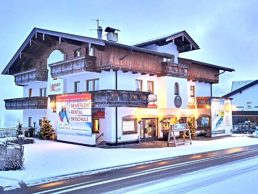 a large white building with a balcony in the snow at Apart Heim in Fügen
