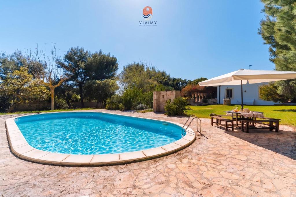 a pool in a yard with a table and an umbrella at Casina dei Capperi by Vivimy in Torre Pali