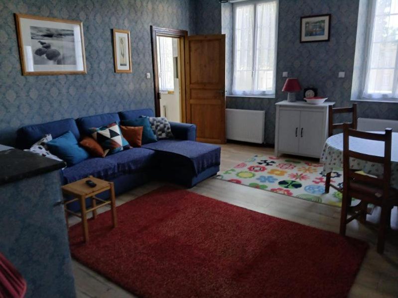 a living room with a blue couch and a red rug at Maison Marcadieu in Maubourguet