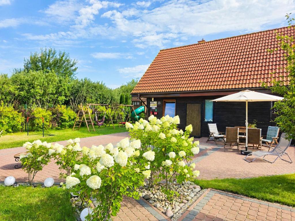 a garden with a house with a table and an umbrella at Morenowa Dolina Rusinowo in Rusinowo