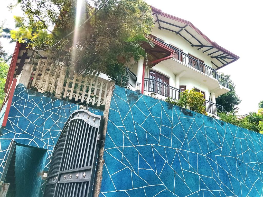 a building with a blue wall with a house at Ciao Villa, Kandy in Kandy