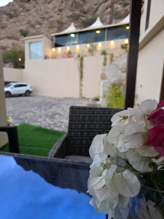 a vase of white flowers in front of a house at Wadi Bani Khalid Guest house in Dawwah