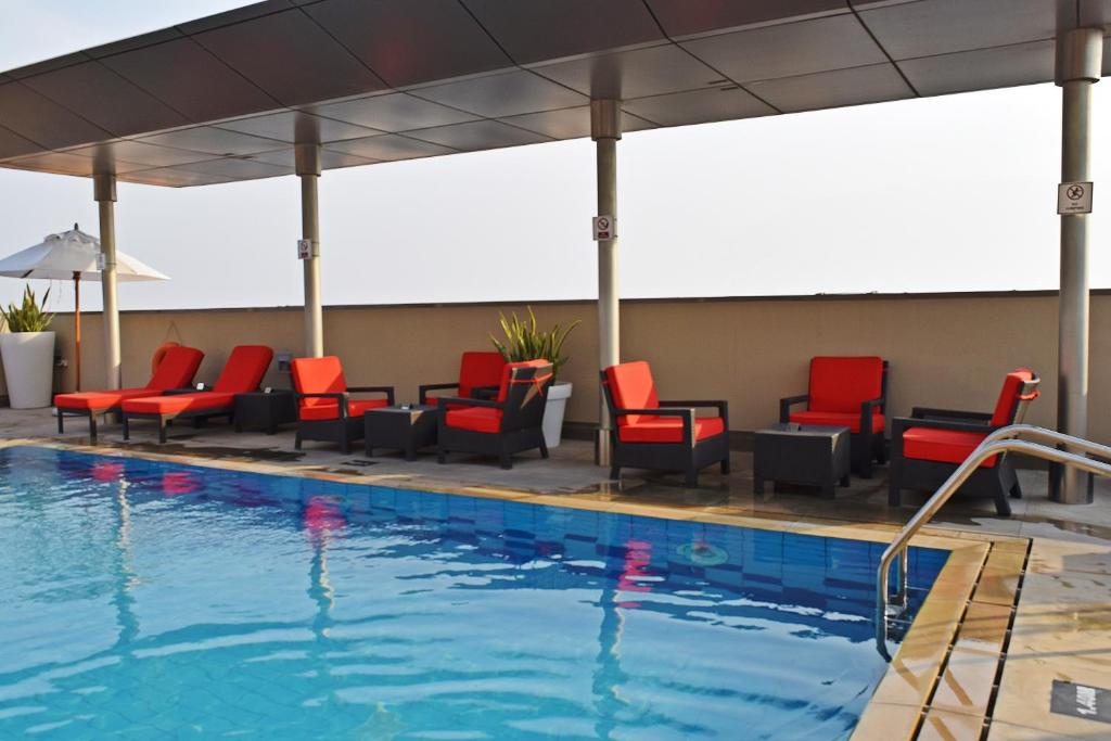 a pool at a hotel with red chairs at Centro Al Manhal by Rotana in Abu Dhabi