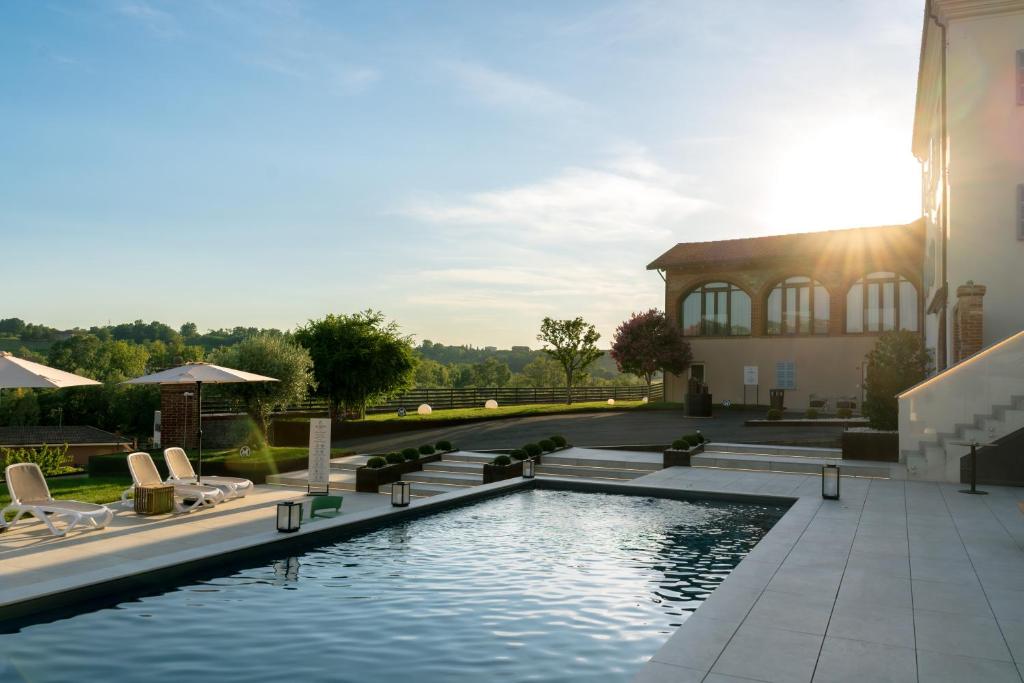 a swimming pool in front of a building at Vinea Relais in Dogliani