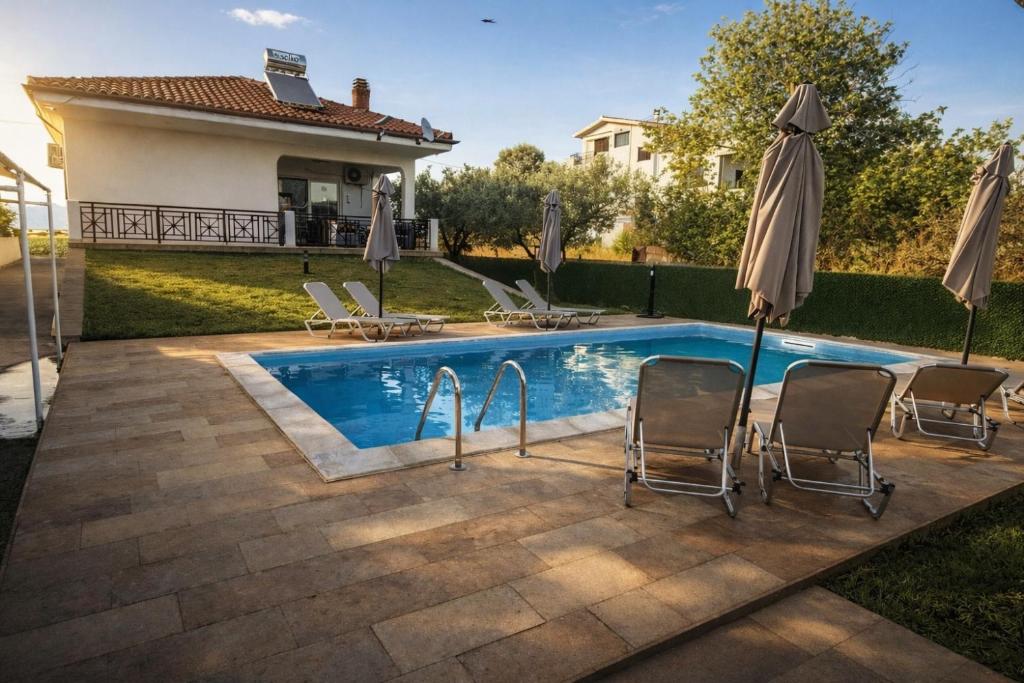 a swimming pool with chairs and an umbrella at My House in Paralia Messi in Aroyí
