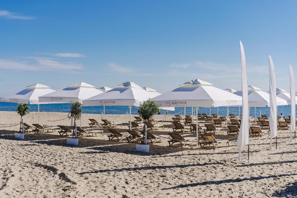 a group of white umbrellas and chairs on a beach at Hotel Haffner Resort & Spa - Destigo Hotels in Sopot
