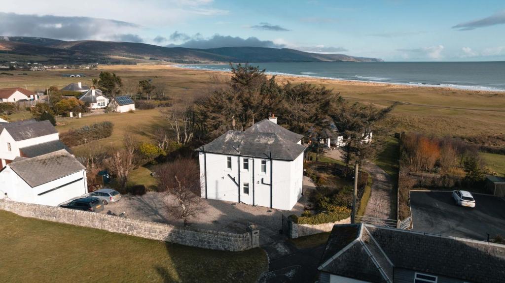 an aerial view of a white house next to the beach at Drumornie in Brora
