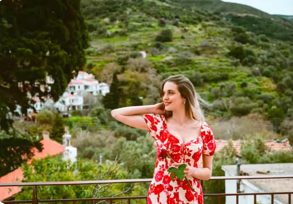 a woman in a red dress standing on a balcony at John & Mary's House near Elafonisi Beach in Perivólia