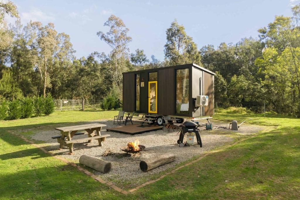 a tiny house with a picnic table and a fire at The Wollombi Wanderer by Tiny Away in Wollombi