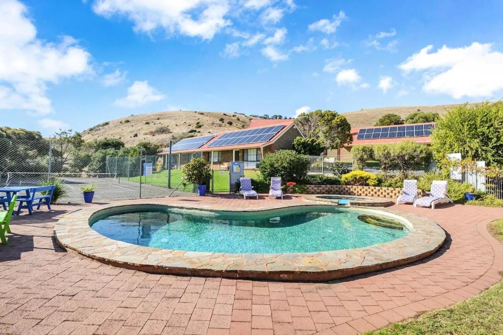 a swimming pool in a patio with chairs and a house at NR 4 Cove Apartment Carrickalinga in Carrickalinga