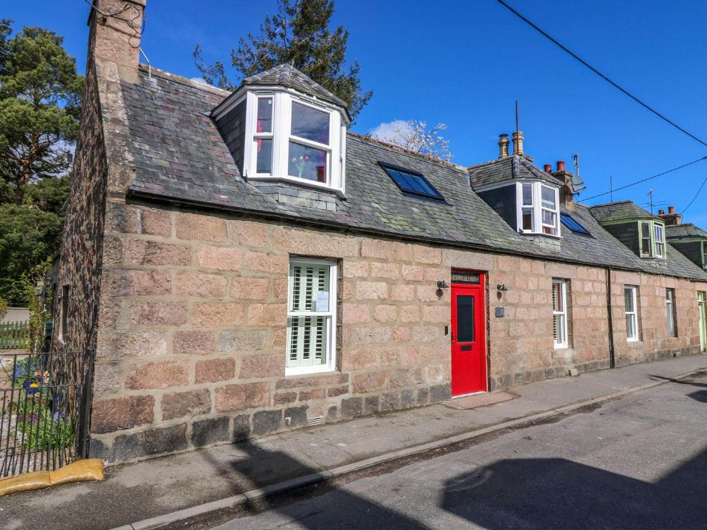 an old brick building with a red door at Evansford in Ballater