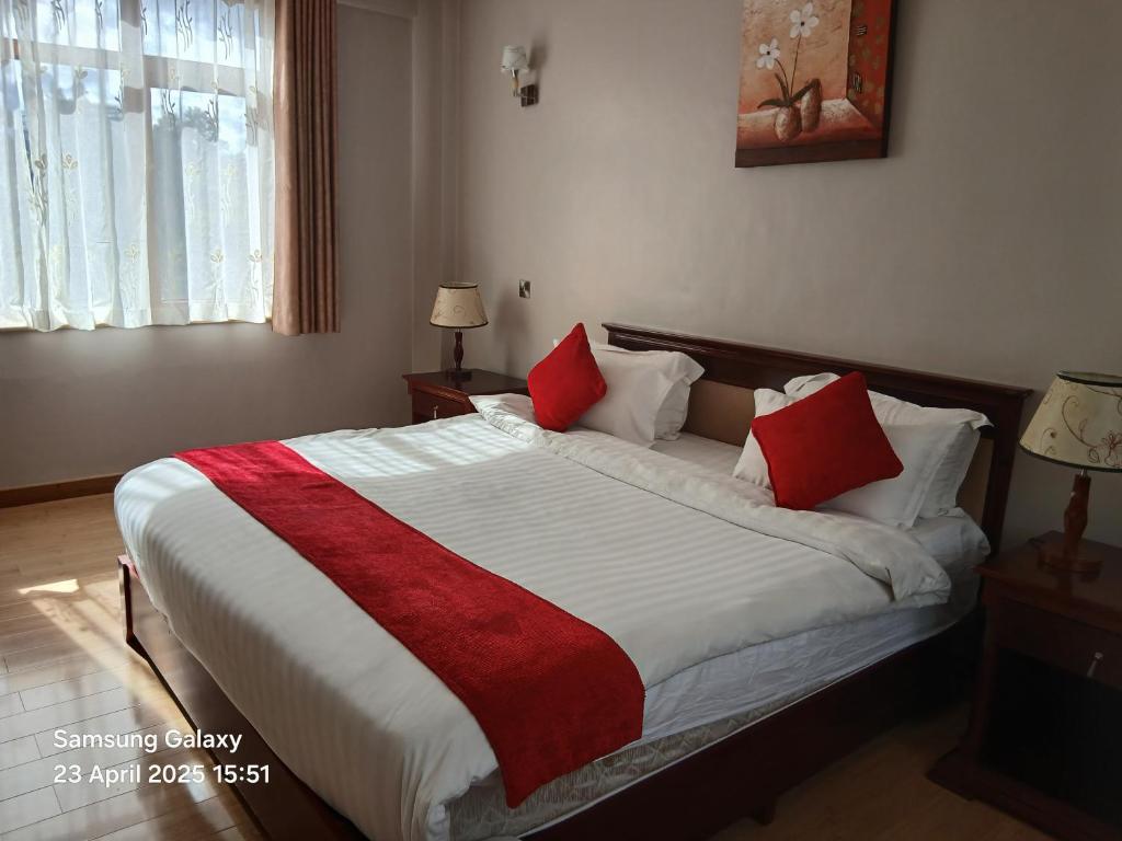 a bedroom with a large bed with red pillows at La Maison Mara in Ololaimutiek