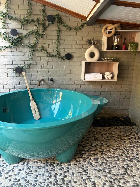 a blue tub in a bathroom with a brick wall at Nest-Dove's Nest in Howick