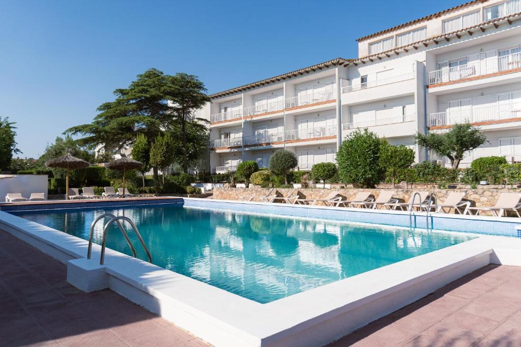 a swimming pool in front of a building at RVApartaments Escala Brava in L'Escala