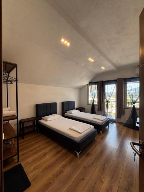 two beds in a room with wooden floors and windows at ARBI GUEST House in Kukës