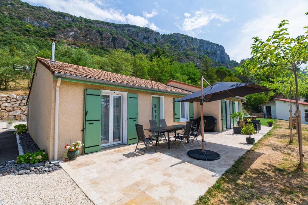 a small house with a table and an umbrella at Le Beauregard - Piscine in Beauregard-Baret