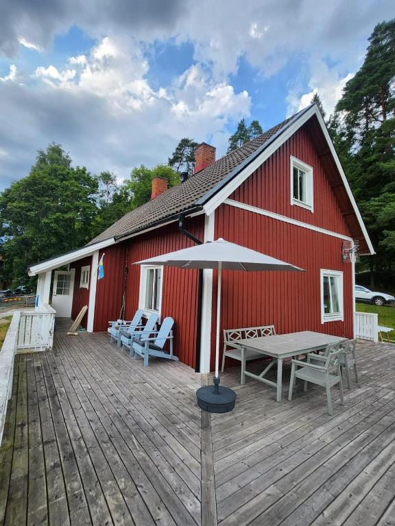 a red barn with a picnic table and an umbrella at StayinDalsland in Dals Långed