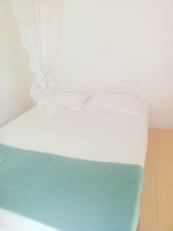a white bed with white sheets and pillows on it at Obama homestay in Riung