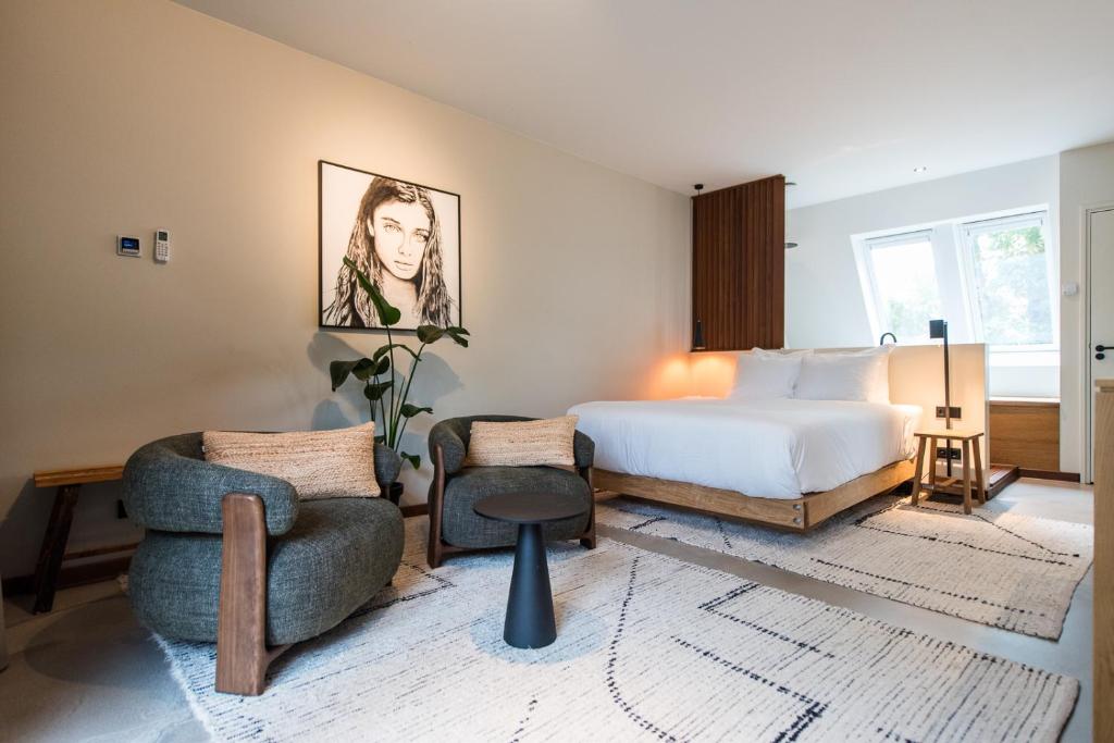 a bedroom with a bed and two chairs at Van Heeckeren City Centre Jacuzzi Lofts in Nes