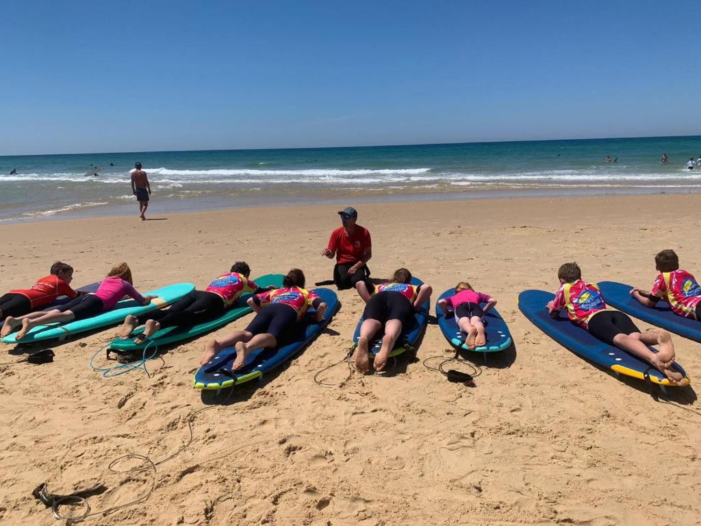 a group of people laying on surfboards on the beach at Le Carrefour des Landes in Mimizan-Plage