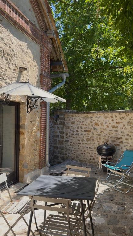 a table and chairs and an umbrella on a patio at Studio duplex avec spa et cour privée in Bonnelles