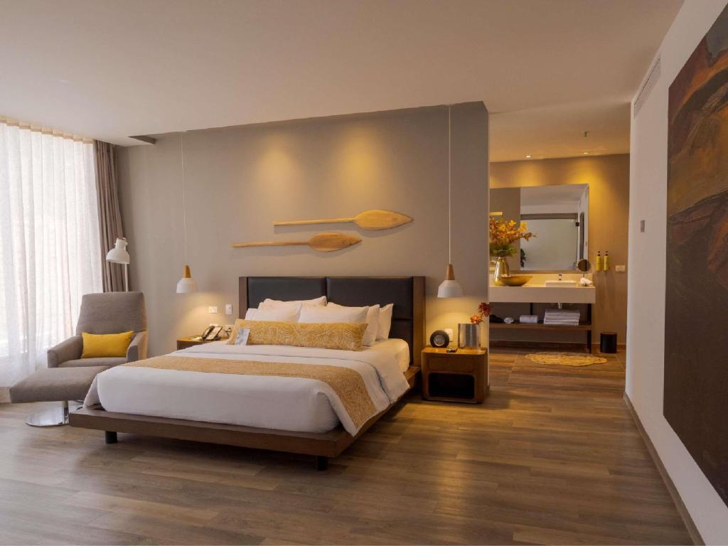 a bedroom with a bed and a chair and a mirror at Novotel Medellin El Tesoro in Medellín