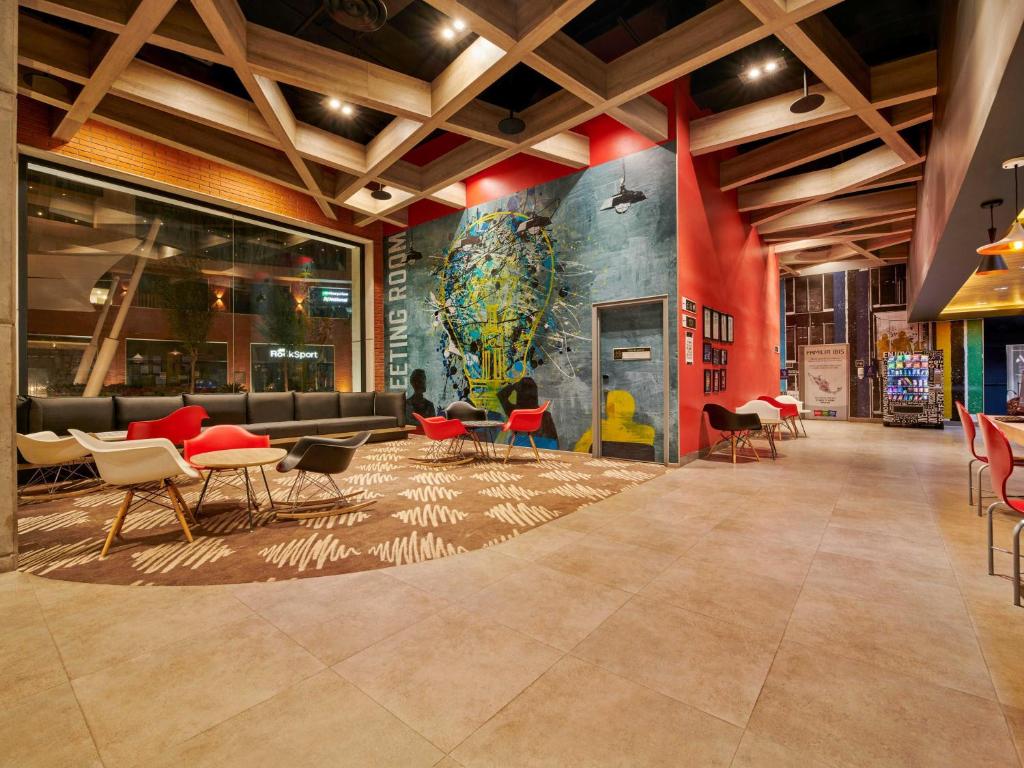 eine Lobby mit Tischen und Stühlen und einem Wandgemälde an der Wand in der Unterkunft Ibis Torreon in Torreón