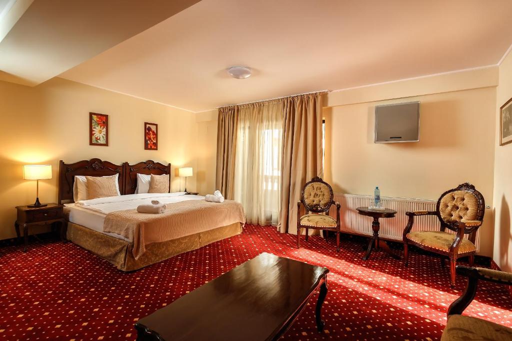 a hotel room with a bed and a table and chairs at Classic Inn Hotel in Braşov