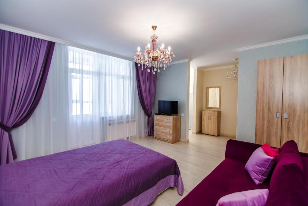 - une chambre avec un lit violet et un canapé dans l'établissement Apartments Promenade Expo, à Astana
