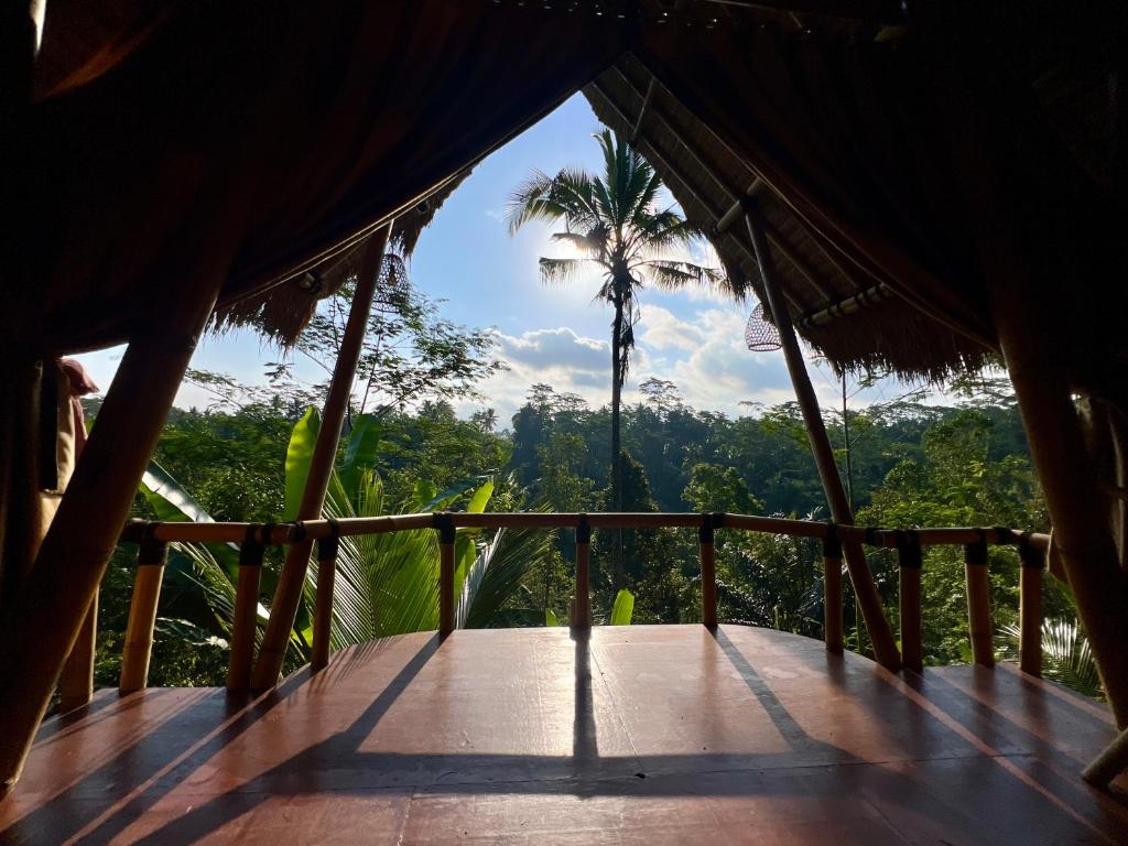 a porch of a hut with a palm tree in the background at Rafka Bamboo Valley in Seribatu