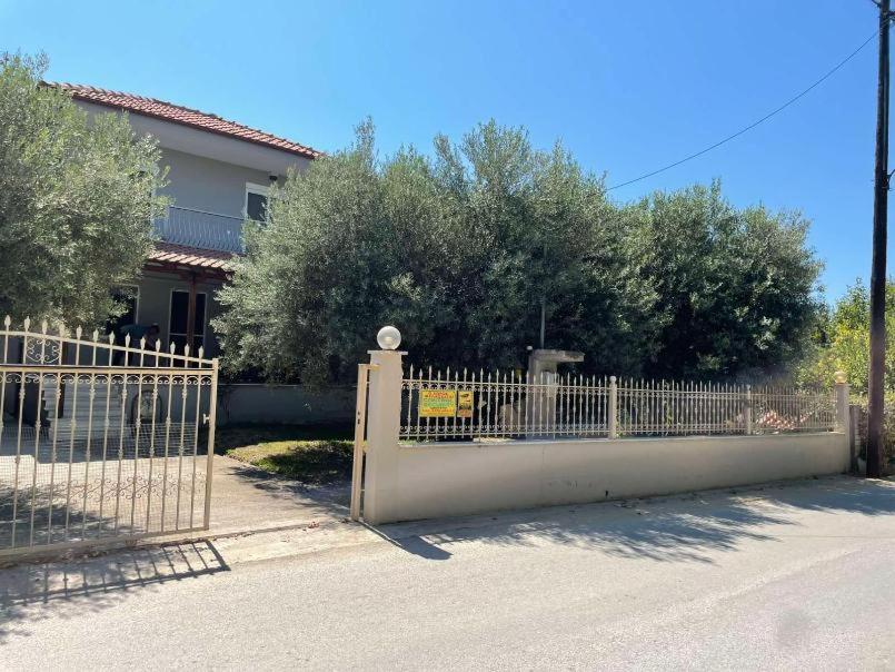 a fence in front of a house with trees at Betty's Seaside Olive House in Ofrínion