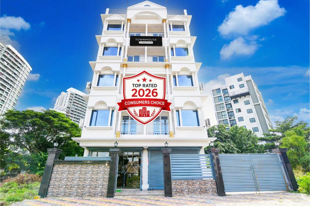 a tall white building with a sign on it at Super Townhouse Rosedale Formerly Reliance Guest House in Kolkata