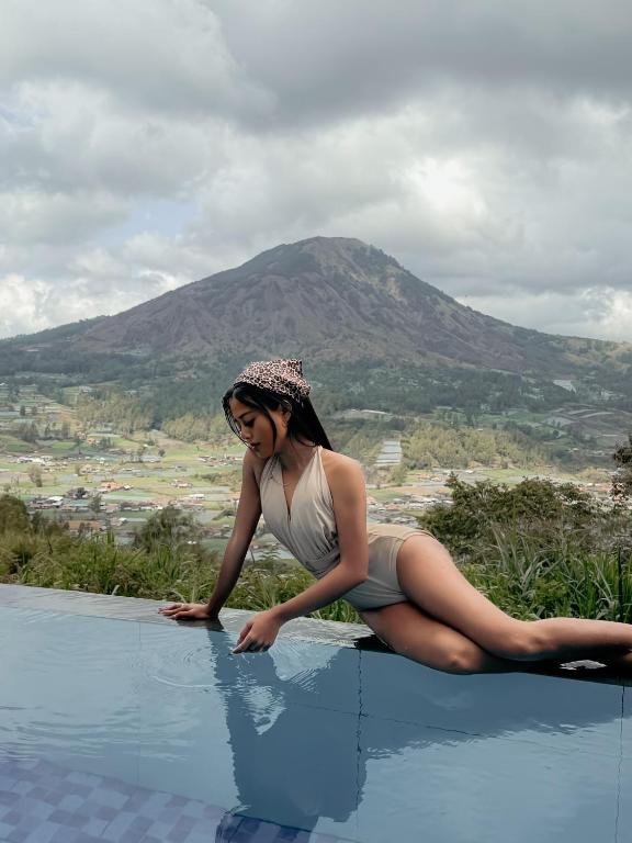 Eine Frau liegt am Rand eines Schwimmbeckens in der Unterkunft Pinggan Infinity - Private Pool Villa in Kintamani in Gretek