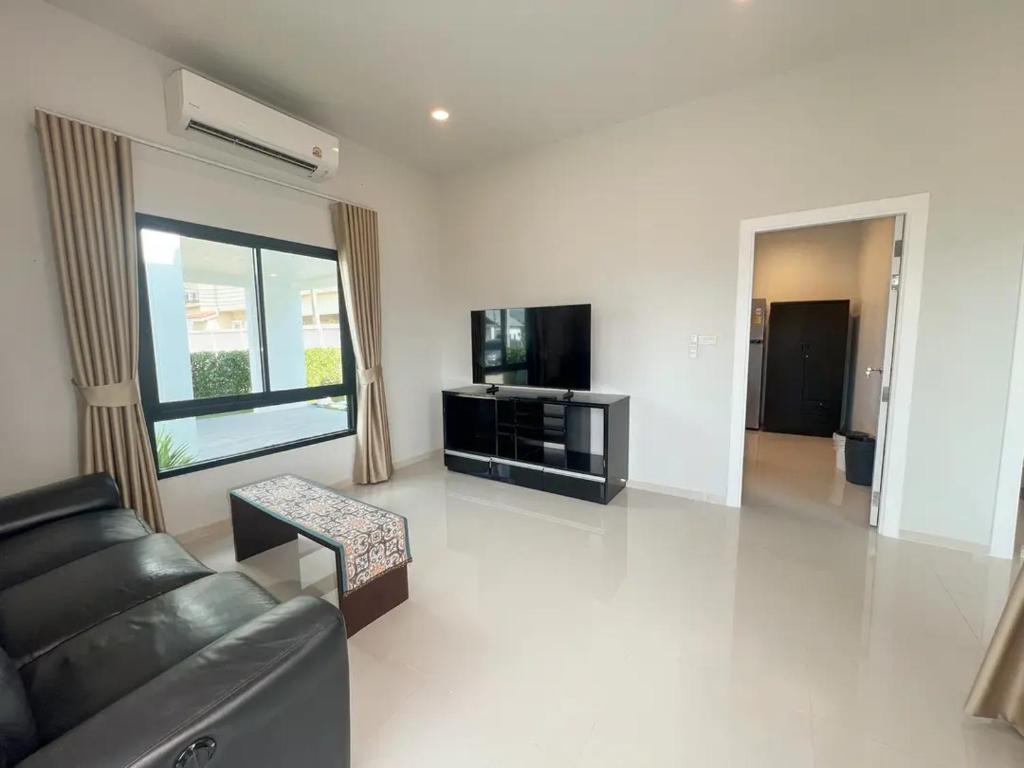 a living room with a black couch and a tv at Indigo Garden Villa by Somjai in Ban Tha Fat