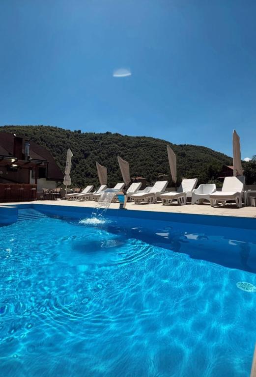 a swimming pool with chairs and blue water at Apartmani Sunce Stara planina in Crni Vrh