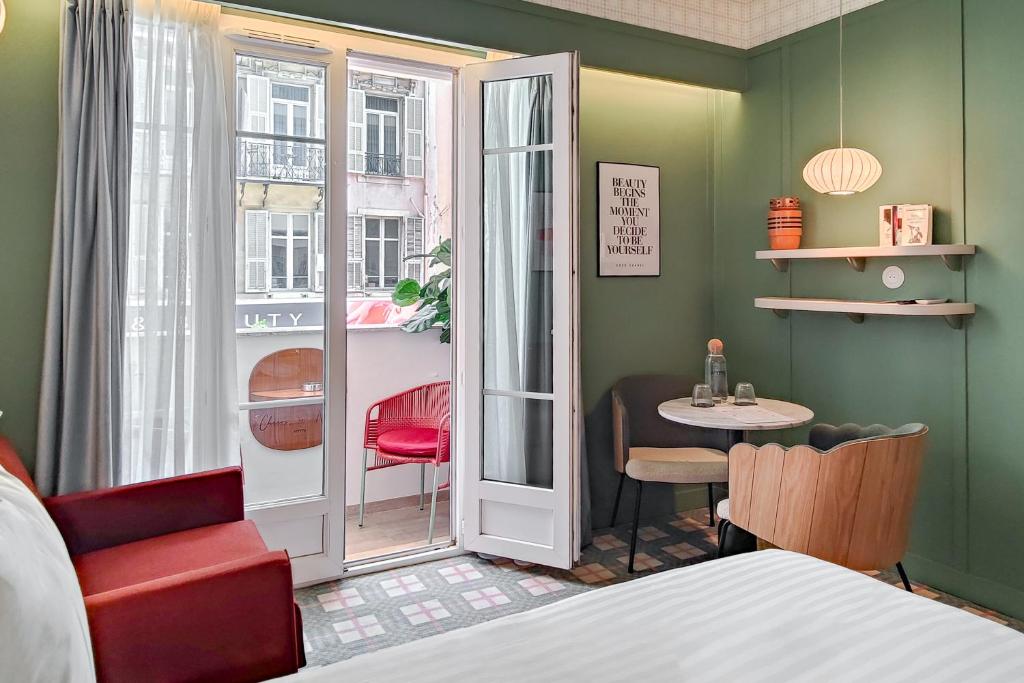 a bedroom with a bed and a table and a window at Hotel Aparthotel AMMI Nice Lafayette in Nice