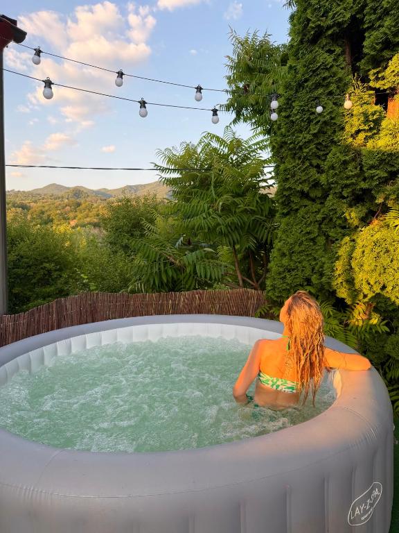 a woman sitting in a jacuzzi tub in a backyard at Casa NIB Calimanesti in Călimăneşti