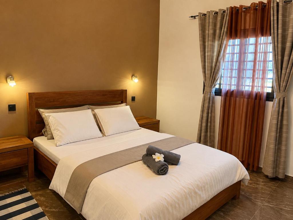 a bedroom with a bed with a teddy bear on it at Le havre des palmiers in Tsivonoabe