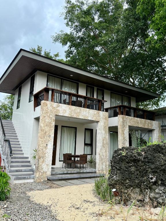 a large white house with a balcony and stairs at Anaya Villas Resort in Bantayan Island