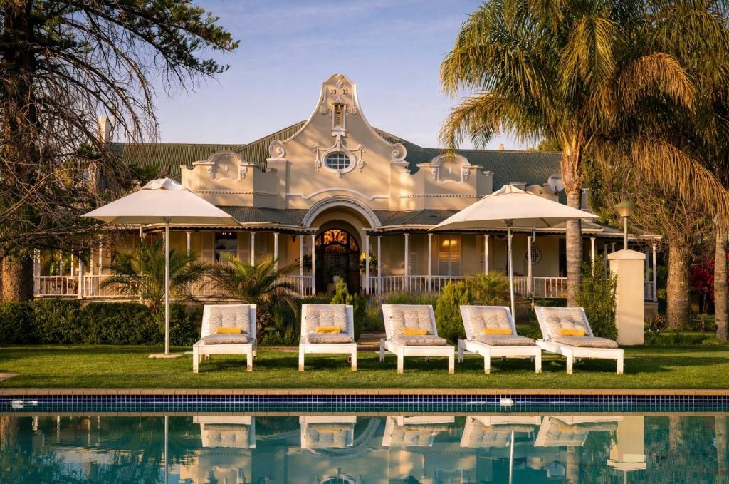 a house with a swimming pool in front of it at Bakenskraal Ostrich Palace in Oudtshoorn