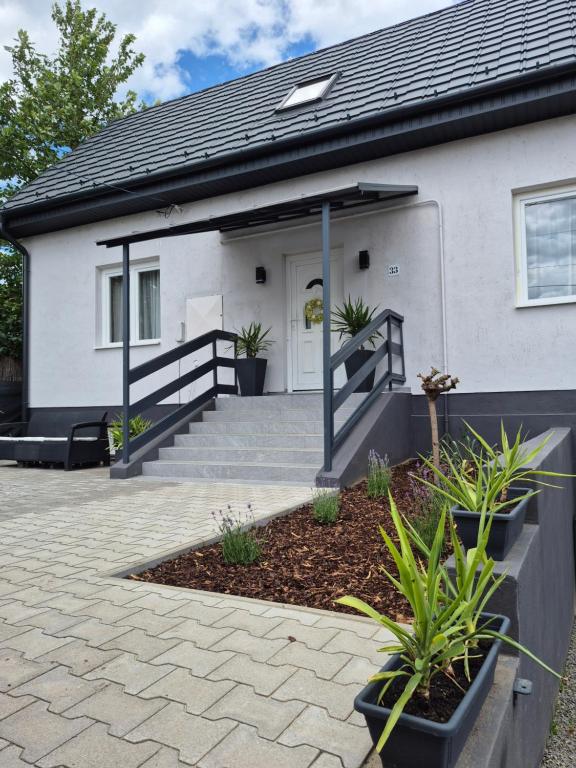 a white house with a porch and a driveway at Kriszta Gold Vendégház in Újfehértó