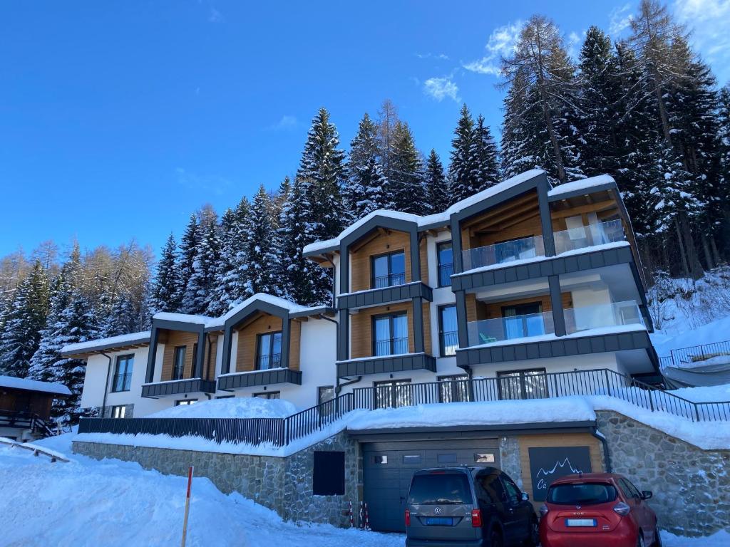 a house in the snow with two cars parked in front at CA del BRENZ in Folgarida