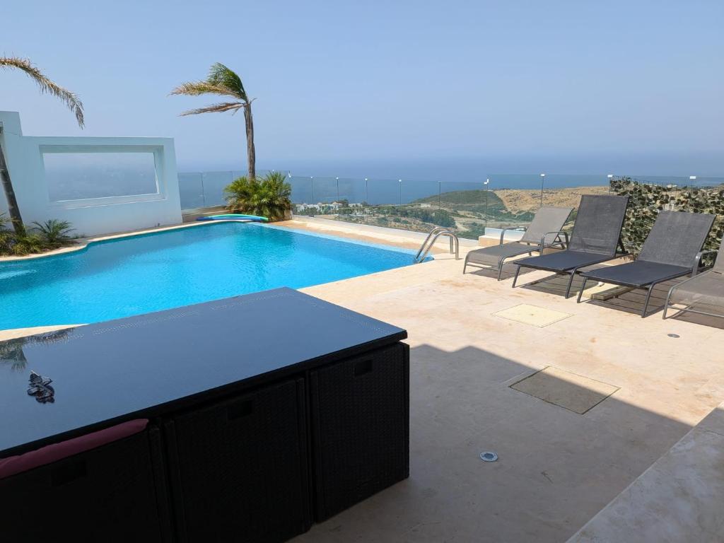 a swimming pool with two chairs and a table at Exclusive luxury villa private pool and garden mnar in Tangier