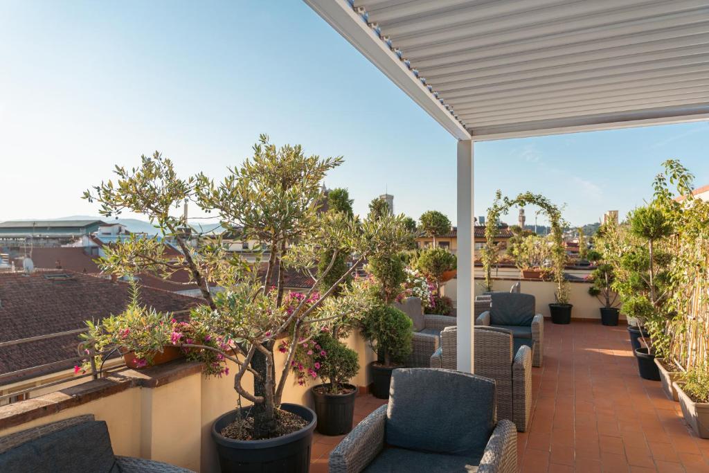 a patio with chairs and trees on a roof at Hotel Annabella Roof Terrace in Florence