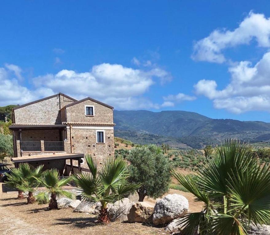 a stone house with palm trees and mountains in the background at Casolare La Mirabella 